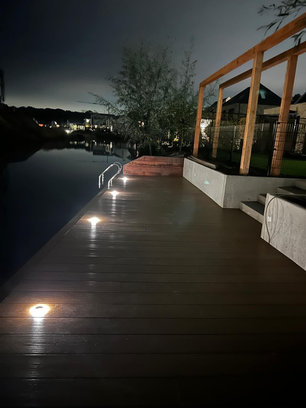 Vlonder aan het water met ingebouwde grondspots in de avond