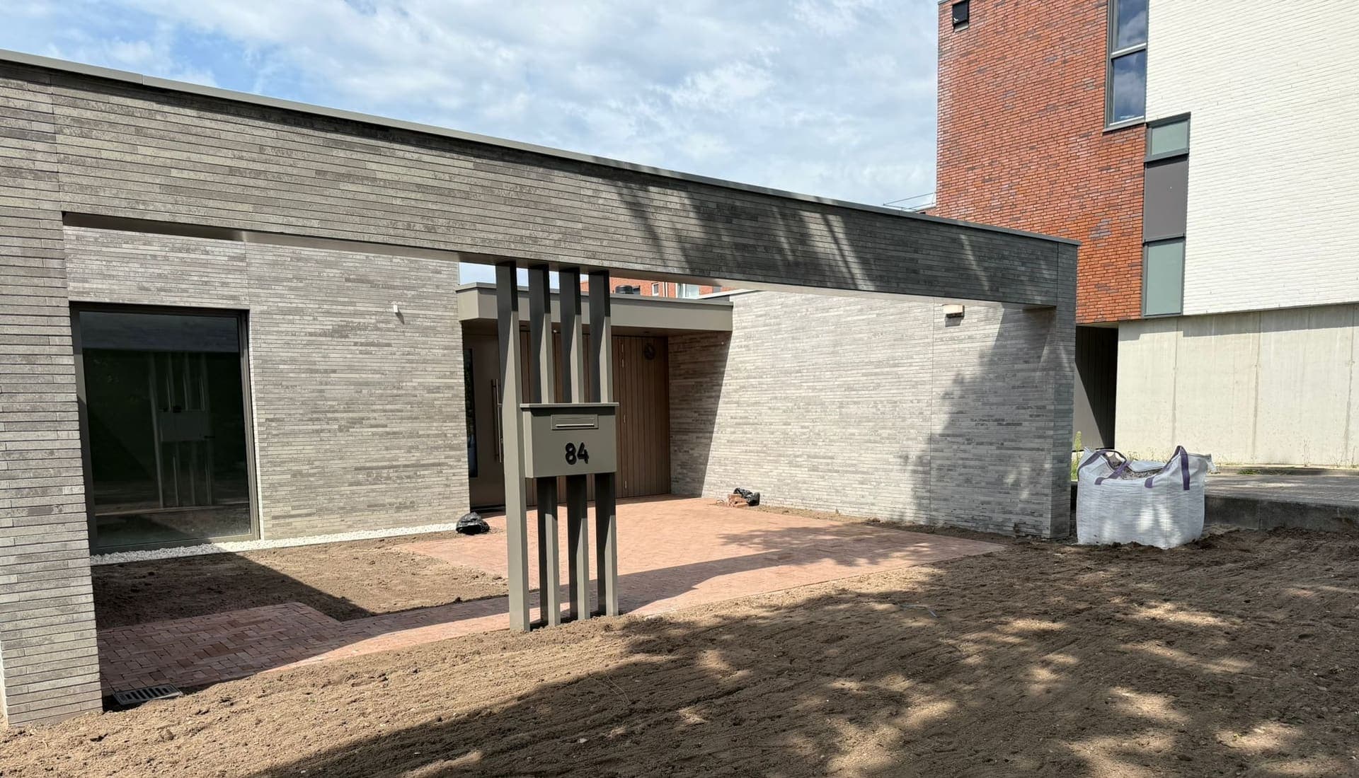 Voorbereid grondwerk en nieuwe klinkerbestrating bij een moderne woning
