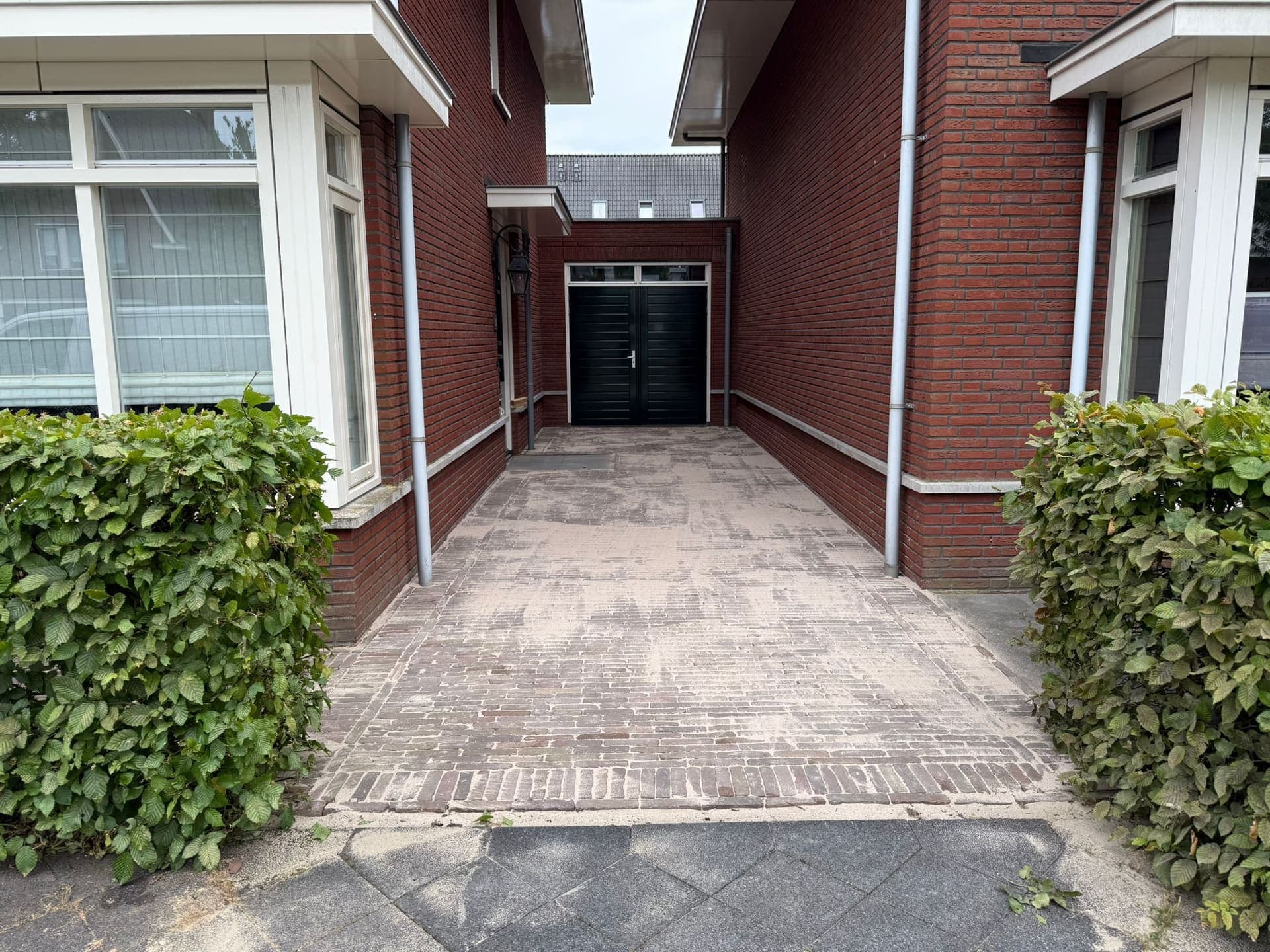 Strak bestraatte oprit van gebakken klinkers tussen twee woningen