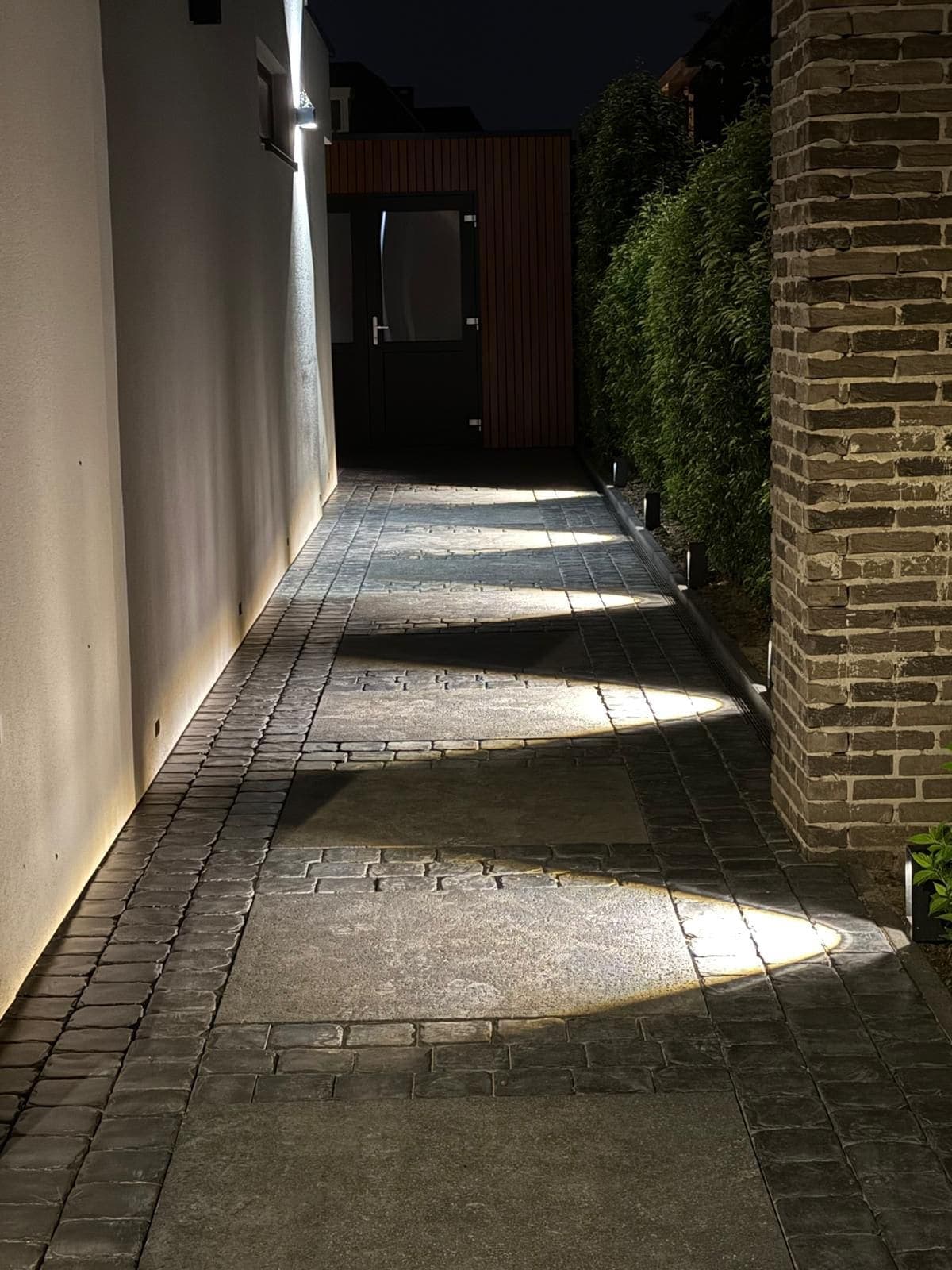 Sfeervol verlichte tuin met grondspots in de avond